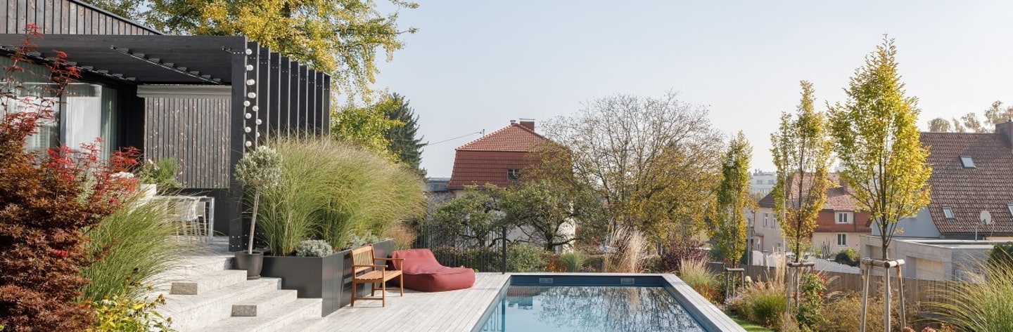 Garten mit Pool und ansprechender Gartengestaltung, im Hintergrund Aussicht über Urfahr